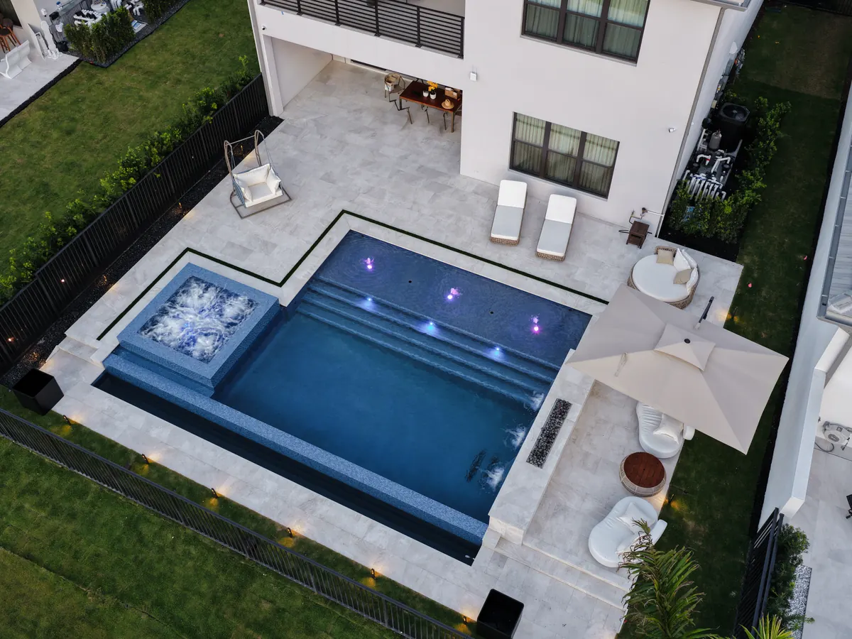Aerial view of an infinity edge pool with spa and LED-lit sunshelf in Boca Raton, FL