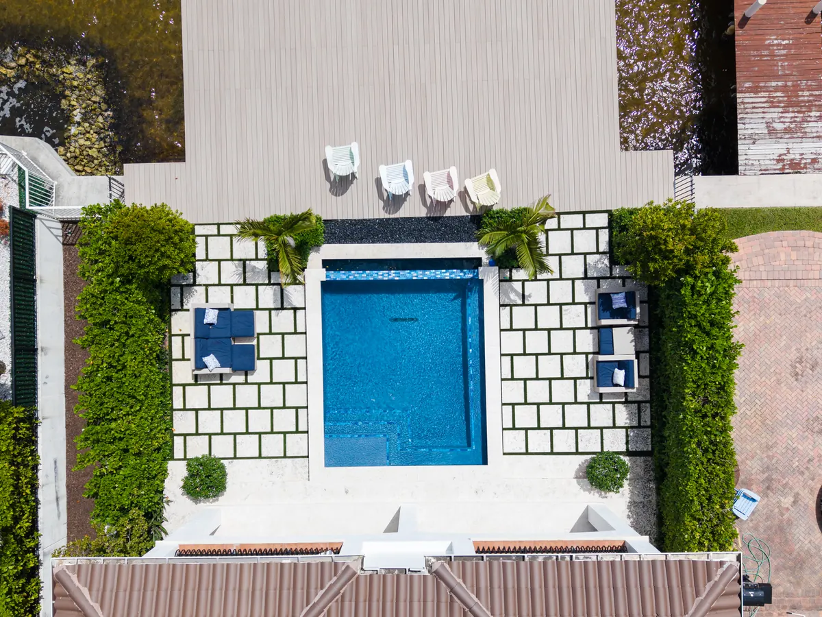 Aerial view of a new backyard pool framed by patterned tile decking in Boynton Beach, FL